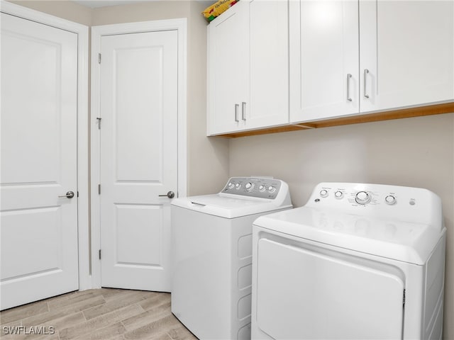 laundry area featuring light wood-type flooring, cabinets, and washer and dryer