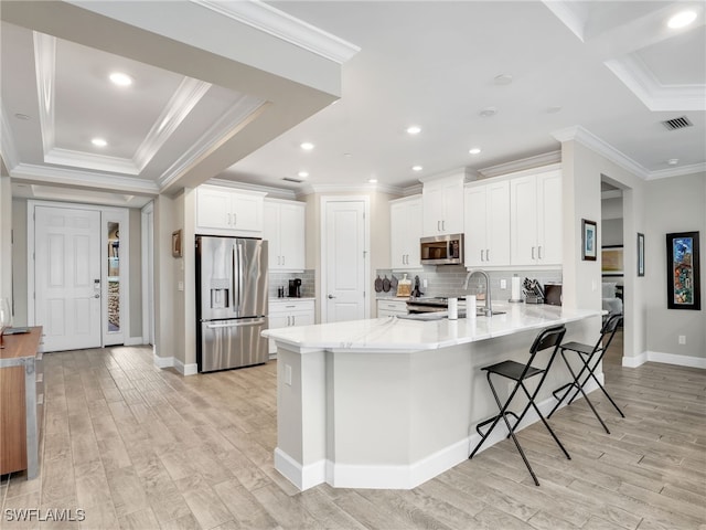 kitchen with light hardwood / wood-style floors, stainless steel appliances, sink, kitchen peninsula, and white cabinetry