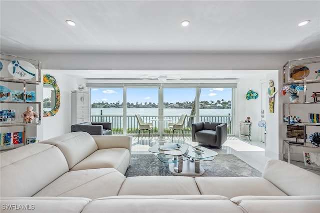 living room featuring a water view, ceiling fan, and plenty of natural light