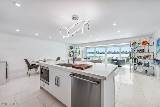 kitchen featuring sink, an island with sink, white cabinets, appliances with stainless steel finishes, and light tile patterned floors