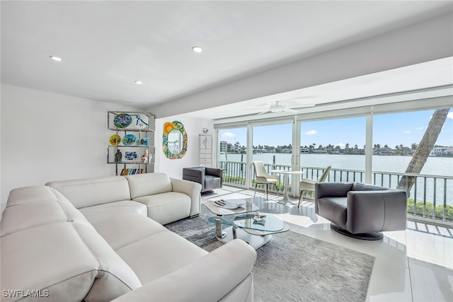 living room featuring ceiling fan and a water view