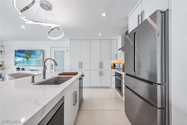 kitchen featuring light tile patterned flooring, sink, white cabinetry, appliances with stainless steel finishes, and light stone countertops