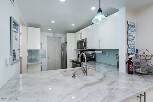 kitchen featuring white cabinets, hanging light fixtures, sink, tasteful backsplash, and appliances with stainless steel finishes