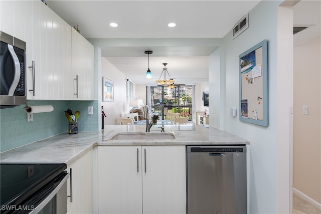 kitchen with sink, decorative light fixtures, white cabinetry, appliances with stainless steel finishes, and light stone countertops