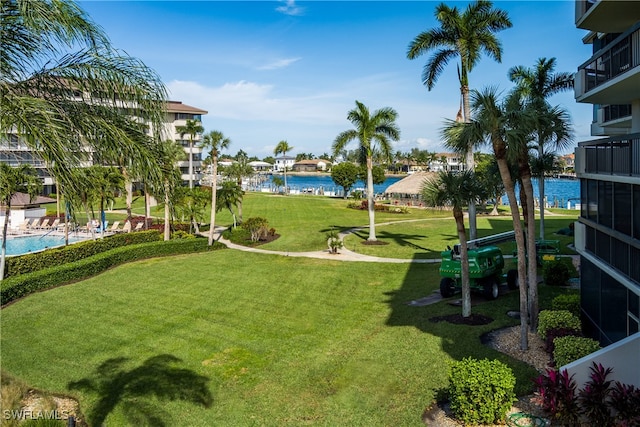 view of property's community featuring a swimming pool, a lawn, and a water view