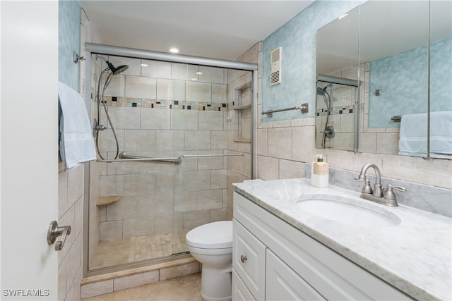 bathroom with vanity, toilet, walk in shower, tile walls, and tile patterned flooring