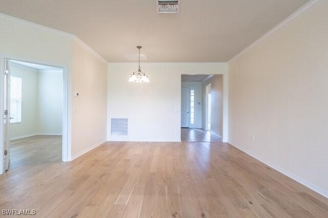 unfurnished room featuring light wood-type flooring, ornamental molding, and a notable chandelier