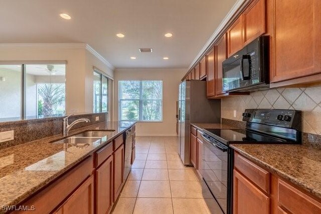 kitchen with light stone counters, sink, backsplash, black appliances, and crown molding