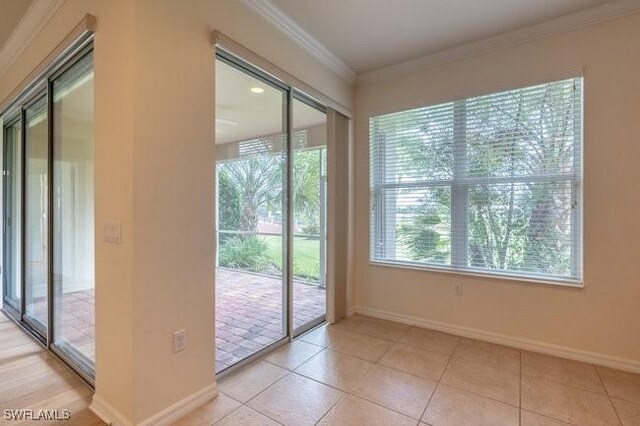 doorway to outside with ornamental molding and light tile patterned floors