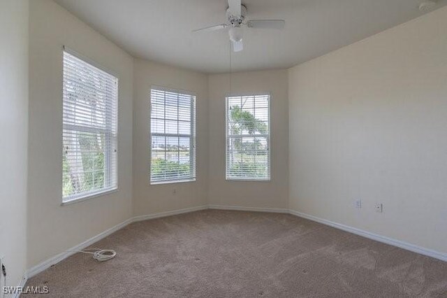 carpeted spare room featuring ceiling fan