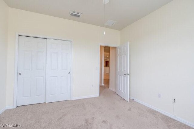 unfurnished bedroom with light carpet and a closet