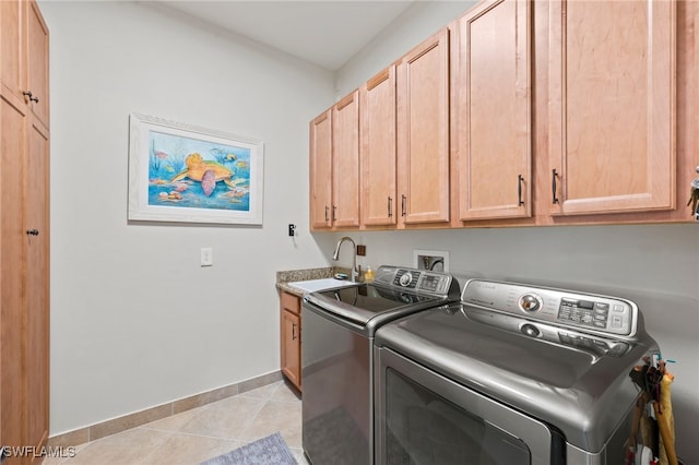 clothes washing area featuring light tile patterned flooring, sink, independent washer and dryer, and cabinets