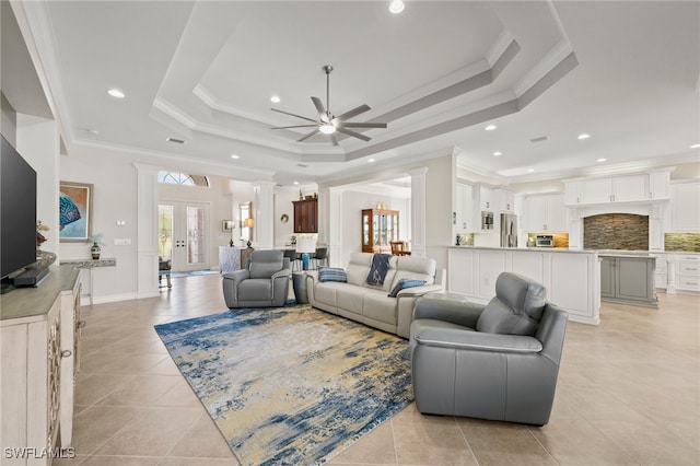 tiled living room featuring ceiling fan, a tray ceiling, french doors, and ornamental molding