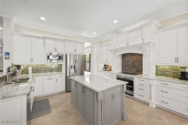 kitchen featuring white cabinetry, backsplash, stainless steel appliances, a center island, and sink