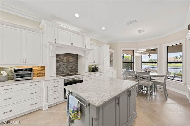 kitchen with white cabinetry, a center island, light tile patterned floors, and backsplash