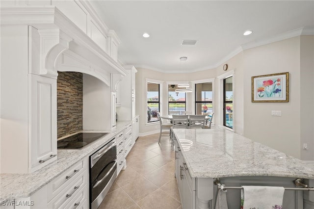 kitchen featuring white cabinets, light stone counters, light tile patterned floors, and decorative light fixtures