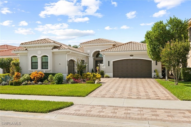 mediterranean / spanish-style home featuring a front lawn and a garage