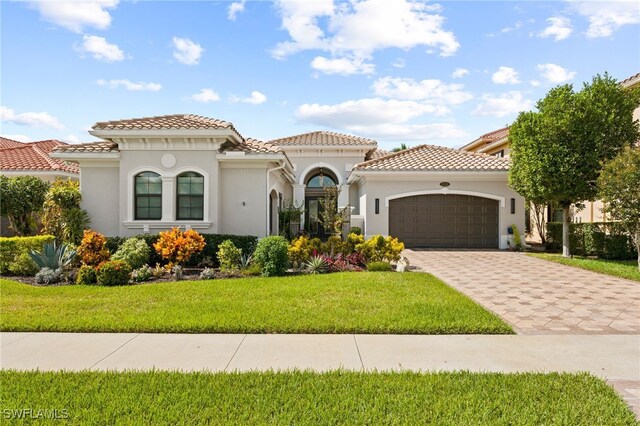 mediterranean / spanish home featuring a front yard and a garage