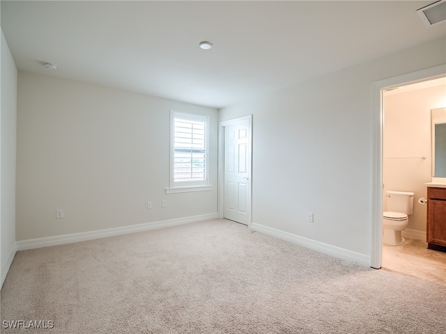 unfurnished bedroom with light colored carpet and ensuite bath