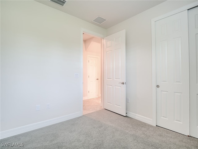 unfurnished bedroom featuring light carpet and a closet