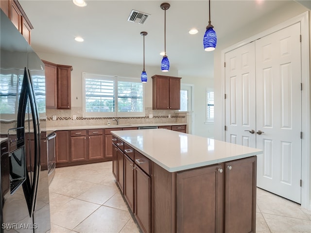 kitchen with hanging light fixtures, stainless steel appliances, sink, a center island, and tasteful backsplash