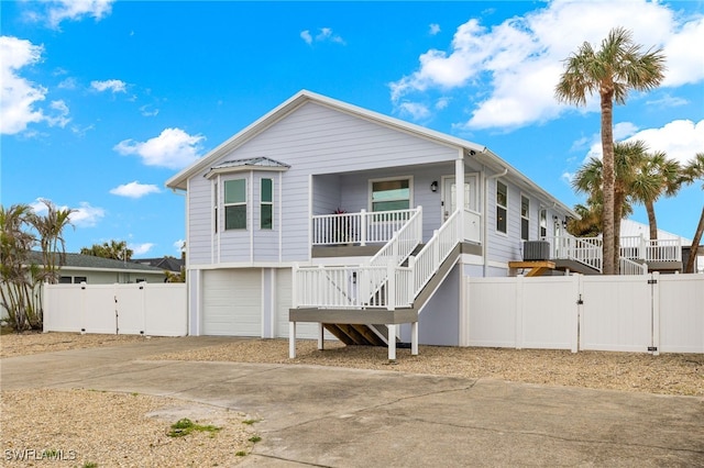 view of front of house featuring concrete driveway, stairway, a gate, fence, and a porch