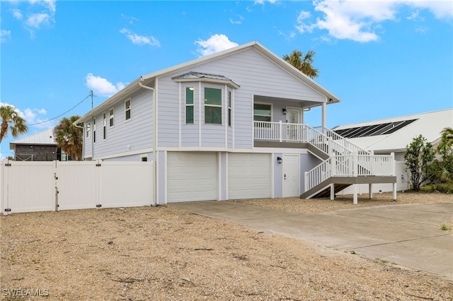 view of front of property with a porch, a garage, stairs, driveway, and a gate