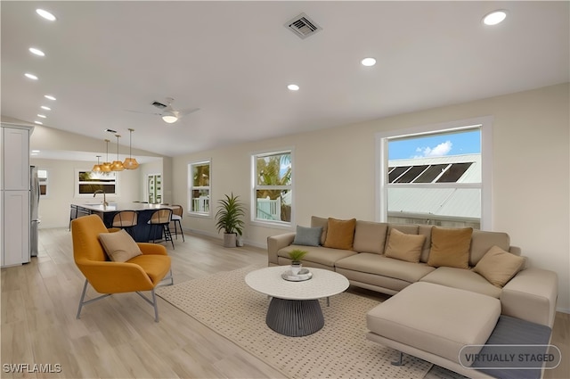 living room with light hardwood / wood-style flooring, lofted ceiling, and a healthy amount of sunlight