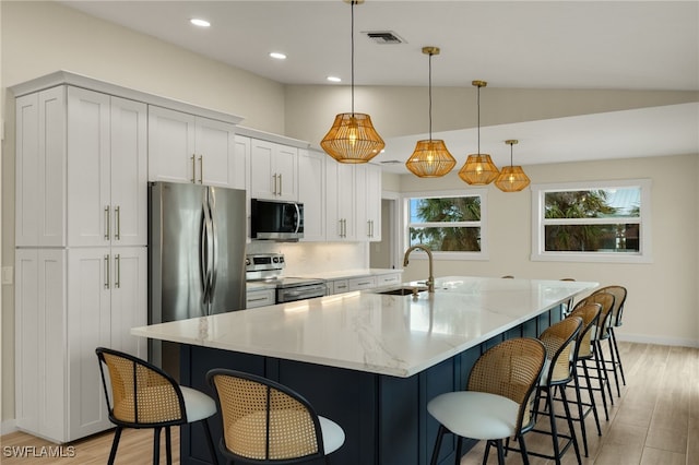 kitchen with a breakfast bar area, stainless steel appliances, a sink, white cabinets, and light wood-type flooring