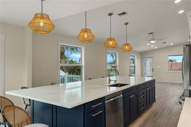 kitchen featuring lofted ceiling, decorative light fixtures, stainless steel appliances, sink, and light wood-type flooring