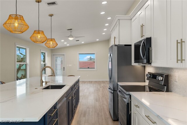 kitchen featuring decorative light fixtures, sink, white cabinetry, and stainless steel appliances