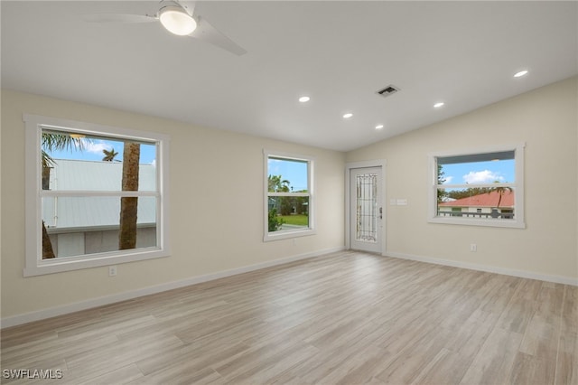 empty room featuring light wood-style flooring, visible vents, vaulted ceiling, and baseboards