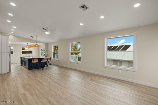 unfurnished living room featuring sink, a wealth of natural light, light hardwood / wood-style floors, and lofted ceiling