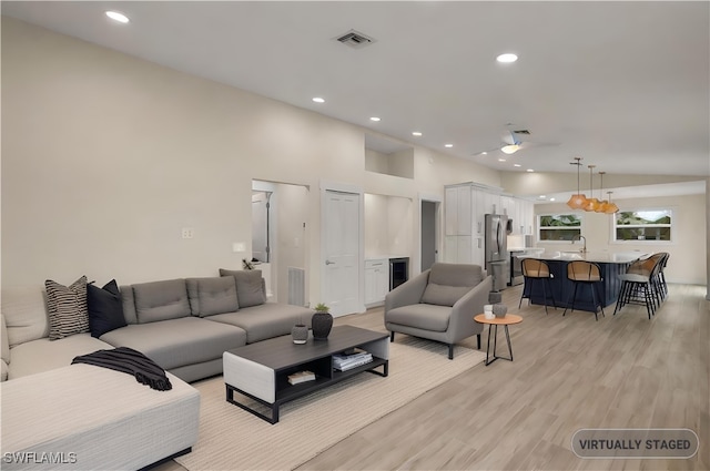 living area with recessed lighting, visible vents, lofted ceiling, and light wood finished floors