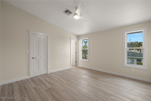 empty room featuring ceiling fan, vaulted ceiling, and light wood-type flooring