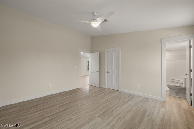 unfurnished bedroom with lofted ceiling, a closet, light wood-style flooring, connected bathroom, and baseboards