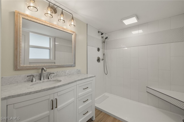 full bath with tiled shower, wood finished floors, and vanity