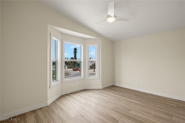 unfurnished room featuring light wood-type flooring, baseboards, a ceiling fan, and lofted ceiling