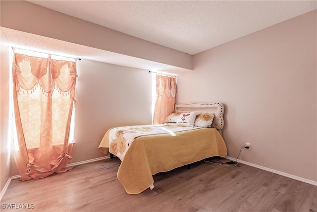 bedroom with light hardwood / wood-style floors and a textured ceiling