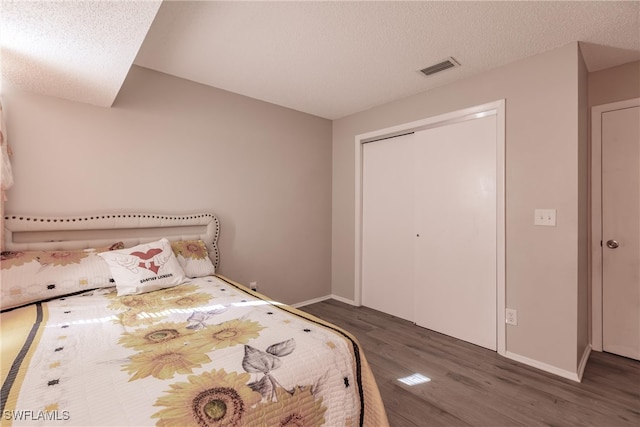 bedroom featuring a textured ceiling, dark hardwood / wood-style floors, and a closet