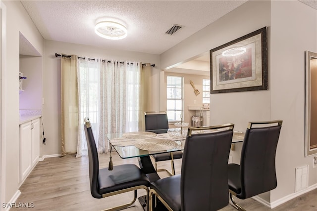 dining room with light wood-type flooring and a textured ceiling