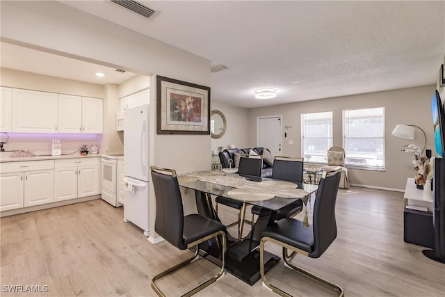 dining room featuring a textured ceiling and light hardwood / wood-style flooring