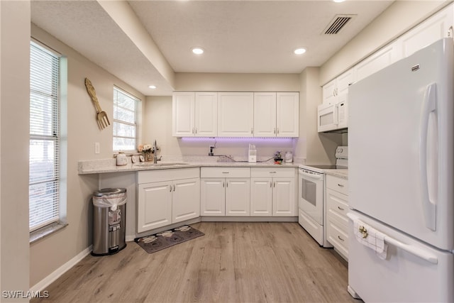 kitchen with white cabinets, light hardwood / wood-style floors, sink, and white appliances