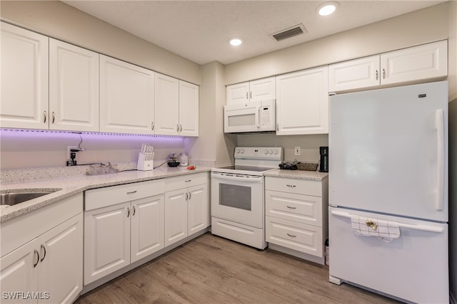 kitchen featuring light stone countertops, white appliances, light hardwood / wood-style floors, and white cabinetry