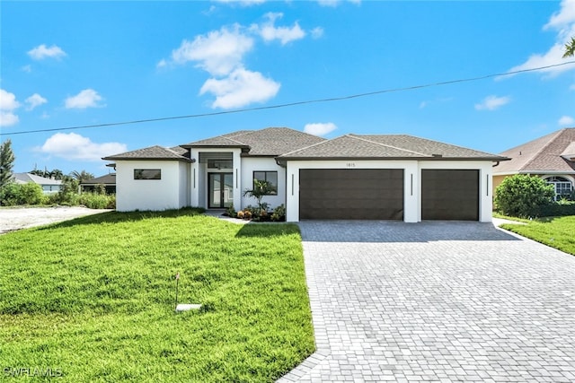 prairie-style house featuring decorative driveway, an attached garage, a front yard, and stucco siding