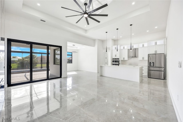 unfurnished living room featuring marble finish floor, visible vents, a high ceiling, and a tray ceiling