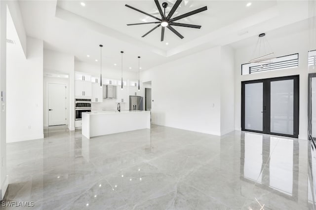 interior space with marble finish floor, french doors, and a raised ceiling