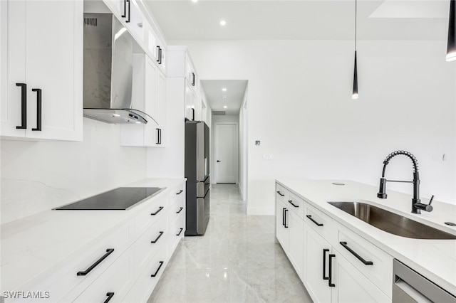 kitchen featuring stainless steel appliances, wall chimney range hood, a sink, and white cabinets