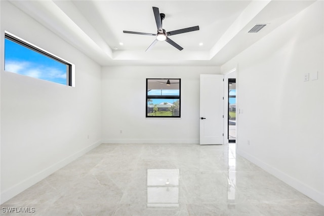 unfurnished room featuring a healthy amount of sunlight, baseboards, a raised ceiling, and recessed lighting