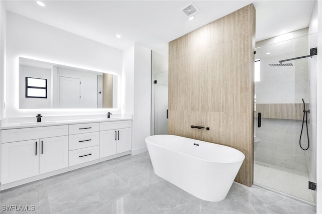 bathroom with a stall shower, a freestanding tub, visible vents, and a sink